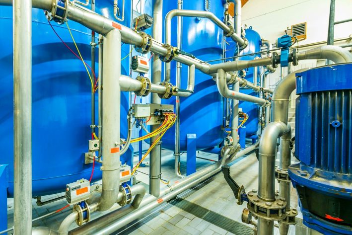 Industrieanlage mit blauen Tanks, Rohrleitungen und Ventilen, die eine komplexe Prozesse steuern.